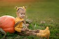 A girl in a strucx jumpsuit is sitting on the grass in the vegetable garden