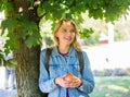 Girl student with backpack hold apple while stand near tree. Healthy snack. Students life concept. Take minute to relax