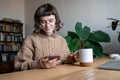 Girl student drinks tea, uses phone. Woman in college library with phone takes break from classes Royalty Free Stock Photo