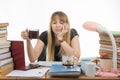 Girl student sadly and sleepily reading his thesis project sitting with a cup of coffee in hand