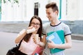 Two happy friends talking, laughing and drinking coffee in front of university campus Royalty Free Stock Photo