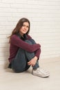 Girl sitting on the floor against a brick wall Royalty Free Stock Photo