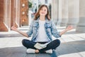 Girl student sitting on the floor and meditating. Girl prays in lotus position