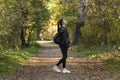 Girl student walks in the autumn park. Stylish young woman walks in the forest. Alley with yellow fallen leaves Royalty Free Stock Photo