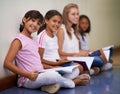 Girl, students and portrait of friends with books sitting at school in hallway for education or learning. Group of young Royalty Free Stock Photo