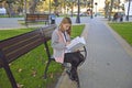 girl studying a book in English on a bench in a city park. additional education Royalty Free Stock Photo