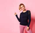 Girl in stylish black long sleeve t-shirt and rose leggings looking forward bending arm in elbow inviting to go in for sports Royalty Free Stock Photo