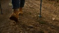 Girl in stylish boots walking on dirt road. Female tourist trekking in mountains Royalty Free Stock Photo