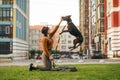 Girl in stylish clothes trains the puppy on a walk in the yard, owner kneels on the lawn, dog jumps into the girl`s hands.Lady Royalty Free Stock Photo