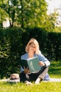 Girl in a stylish ijak holds a folder. The concept of onlay work freelancer outdoors in a big city in the park in the summer