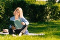 Girl in a stylish ijak holds a folder. The concept of onlay work freelancer outdoors in a big city in the park in the summer