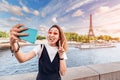 Girl in a stylish outfit and pink glasses takes a selfie photo on the background of the main attractions of Paris - the Royalty Free Stock Photo