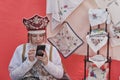 Girl in stylized Russian traditional clothes scrolling cellphone at rural holiday.