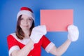 Girl in a suit `Santa Claus` with a sign on a blue background. The concept of discounts and sales for Christmas. Discount on holid