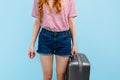 Girl with a suitcase on an isolated blue background. The concept of summer holidays, travel Royalty Free Stock Photo