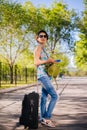 Girl with a suitcase. Model holds a cell phone in his hands. Waiting for a trip