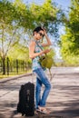 Girl with a suitcase. Model holds a cell phone in his hands. Waiting for a trip