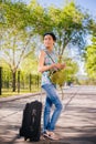 Girl with a suitcase. Model holds a cell phone in his hands. Waiting for a trip