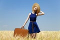 Girl with suitcase at spring wheat field. Royalty Free Stock Photo