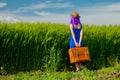 Girl with suitcase standing at wheat field Royalty Free Stock Photo