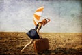 Girl with suitcase and umbrella at field. Royalty Free Stock Photo