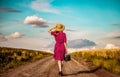 Girl with suitcase waking on rural road