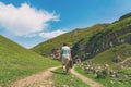 A girl with a suitcase walks along a dirt road in the mountains. Interesting jouney of lonely woman