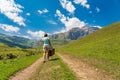 A girl with a suitcase walks along a dirt road in the mountains. Interesting jouney of lonely woman