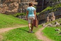 A girl with a suitcase walks along a dirt road in the mountains. Interesting jouney of lonely woman