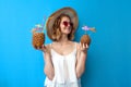 Girl in summer clothes holds tropical cocktails made of pineapple and coconut on a blue isolated background, a woman in a resort Royalty Free Stock Photo