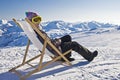 Girl sunbathing in a deckchair on the side of a ski slope Royalty Free Stock Photo