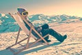 Girl sunbathing in a deckchair on the side of a ski slope, vintage Royalty Free Stock Photo