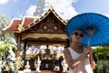 Girl with sunglasses and a blue umbrella in her hands with a happy expression in front of a Buddhist temple Royalty Free Stock Photo