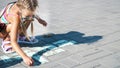 a girl in sunglasses, draws drawings with colored crayons on the asphalt, street tiles. A hot summer day. Royalty Free Stock Photo