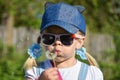 A girl in sunglasses in the field is blowing strongly at a flower dandelion, close-up, summer Royalty Free Stock Photo