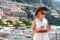 A girl in a sunglasses and a hat stands on the beach in Positano. View of houses and hotels in the background. Use smarphone Royalty Free Stock Photo