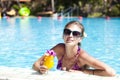 girl in sunglasses with juice in luxury pool