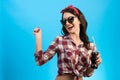 The girl in sunglasses standing with a bottle of drink on the blue background.