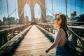 Girl in sunglasses strolls along the Brooklyn Bridge in New York City at sunset