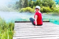 Girl with sunglasses and white hat sitting and enjoying on a wooden pier