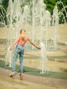 Girl in the Sunny day playing with cool water in city fountain. Royalty Free Stock Photo