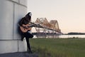 Girl with a guitar standing at the foot of the bridge over the r