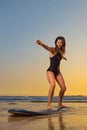 Girl with surf board ready to surfing. Woman surfer holding surfboard on a beach at sunset or sunrise. Surfing at Royalty Free Stock Photo