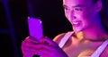 Girl surfing internet on phone in pink neon light