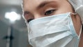 Girl surgeon doctor in surgical mask looks down at patient. Operation, practitioner, operating room, surgery, transplantation, Royalty Free Stock Photo