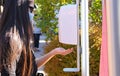 Girl with surgical mask washes her hands with disinfectant gel at the entrance to an outdoor mall. Prevention concept to avoid