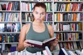 Girl surprised chooses a book in the library Royalty Free Stock Photo