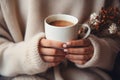 Girl in sweater holds cup of tea or coffee in the morning sunlight. Female hands hold a mug with a hot drink. Generative Royalty Free Stock Photo