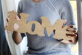 Girl in a sweater holds a sign with the inscription Home. The concept of home comfort