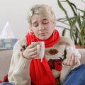 The girl in the sweater is sick and holds a mug with a hot drink. Colds and flu. The patient caught a cold, feeling sick.